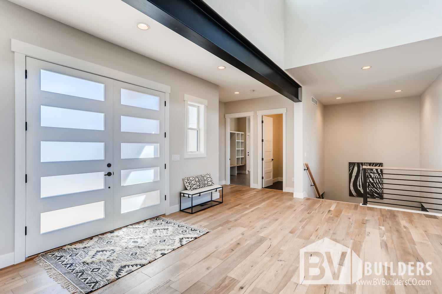 Modern farmhouse entry with explosed steel beam and large five panel french front door