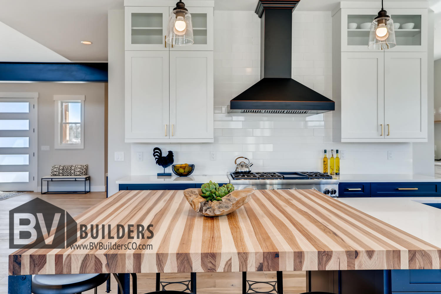 Kitchen island with butcher block, Thermador gas range, white subway tile backsplash and oil rubbed bronze hood