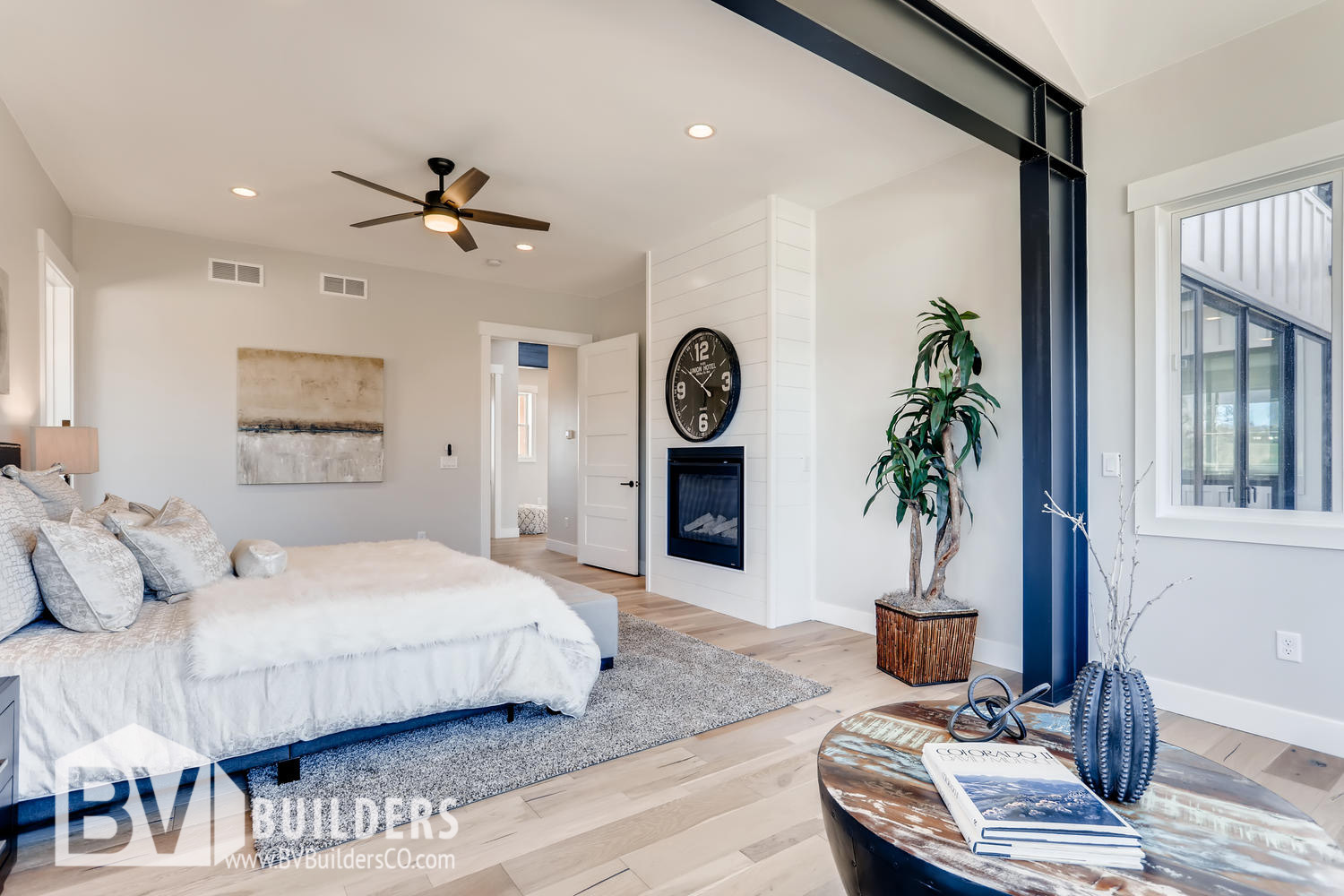 Modern farmhouse master bedroom with exposed steel beams and shiplap fireplace