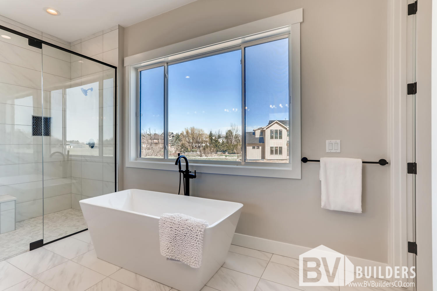 Modern farmhouse master bathroom with soaker tub and glass shower door