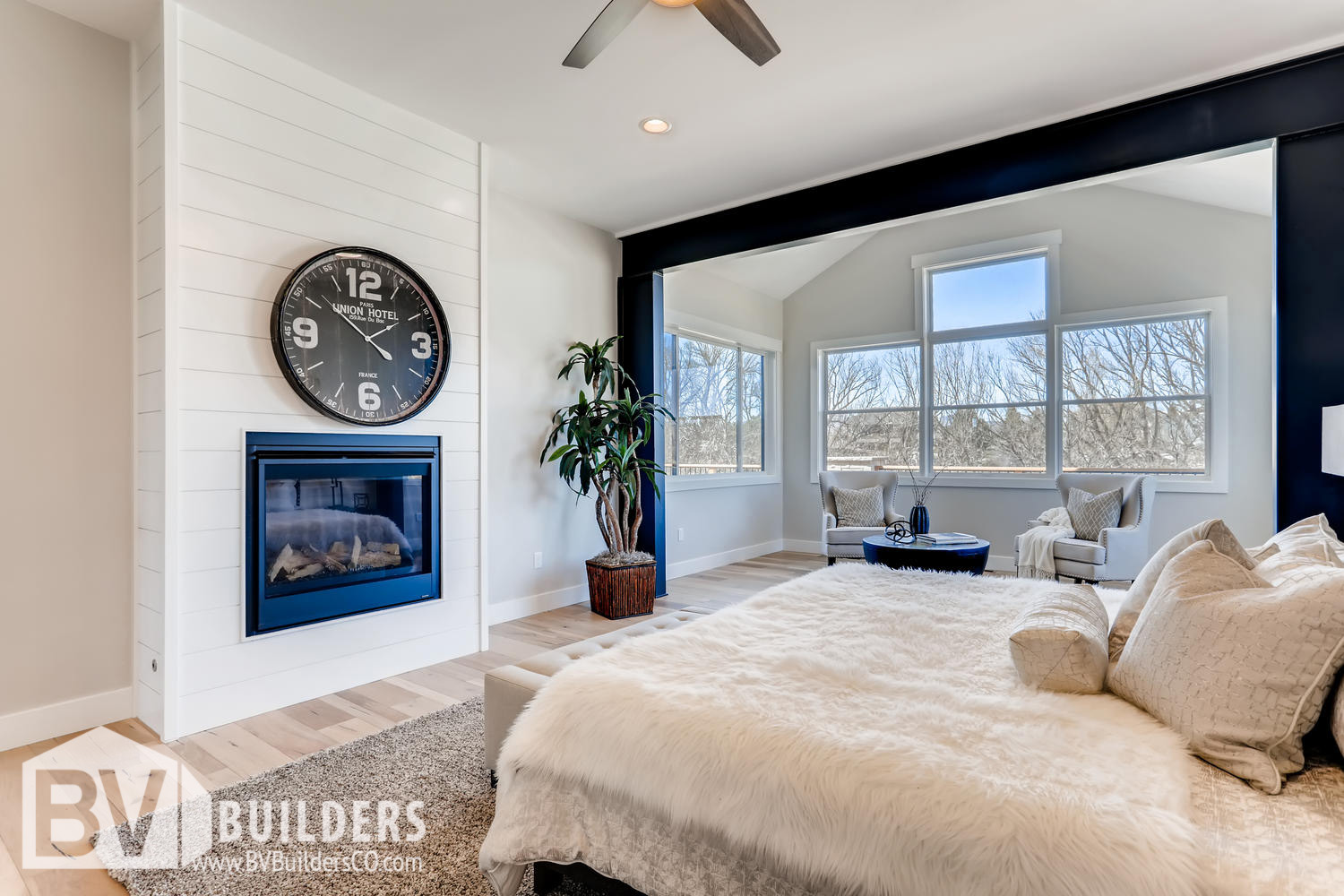 Modern farmhouse master bedroom with exposed steel beams and shiplap fireplace