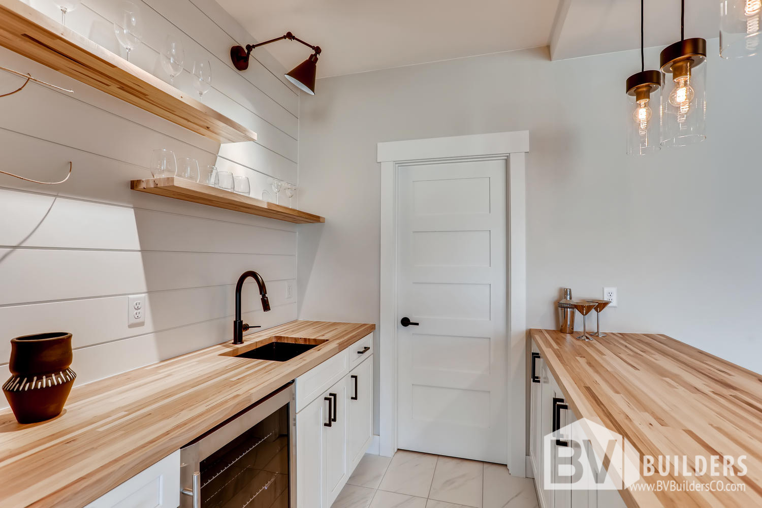 Butcher block wet bar with floating shelves, shiplap backsplash and bar sink