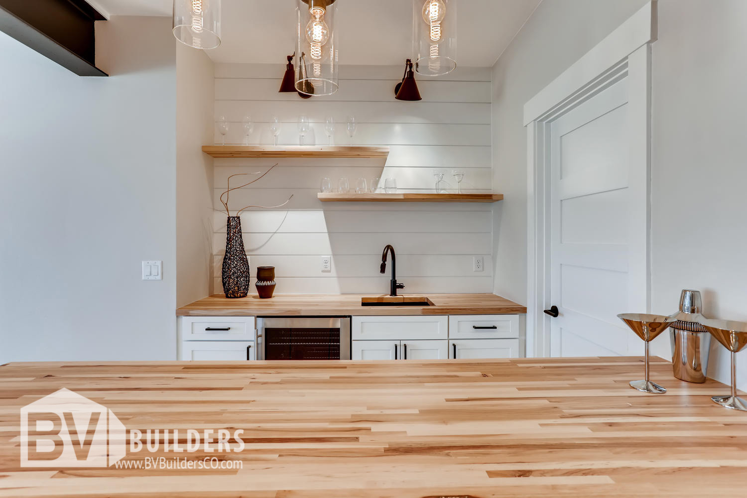 Butcher block wet bar with floating shelves and shiplap backsplash